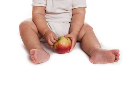 baby with an apple in a white dress on a white backgroundの写真素材