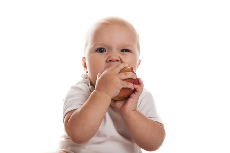 baby with an apple in a white dress on a white backgroundの写真素材