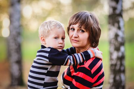 Mother with her son in her arms hugging communicate, play, fall, parkの写真素材