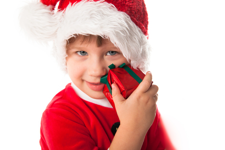 Smiling funny child girl in Santa red hat holding Christmas gift in hands. Christmas concept. play with giftの写真素材
