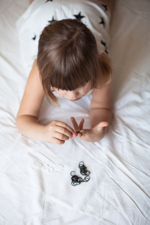 Girl weaves of Rainbow Loom, hobbies, classes for children, on a light background, the dress with the starsの写真素材