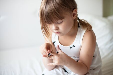 Girl weaves of Rainbow Loom, hobbies, classes for children, on a light background, the dress with the starsの写真素材