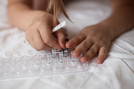 Girl weaves of Rainbow Loom, hobbies, classes for children, on a light background, the dress with the starsの写真素材
