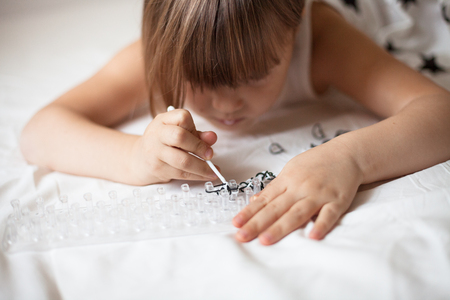 Girl weaves of Rainbow Loom, hobbies, classes for children, on a light background, the dress with the starsの写真素材