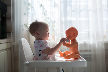 Little child, cute toddler girl having fun playing at home with her dollの写真素材