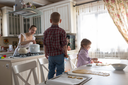 Mother with three kids cooking biscuits in the kitchenの写真素材