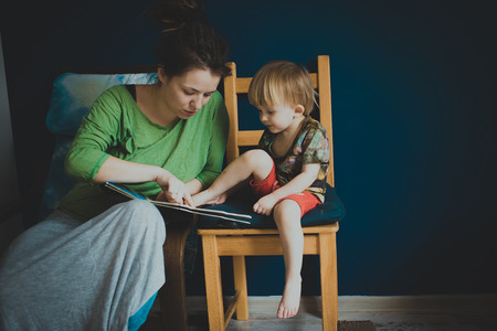 Mother reading with her son at homeの写真素材