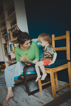 Mother reading with her son at homeの写真素材