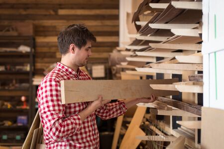 Man carpenter  choosing and buying construction wood in a DIY store chooses wooden board