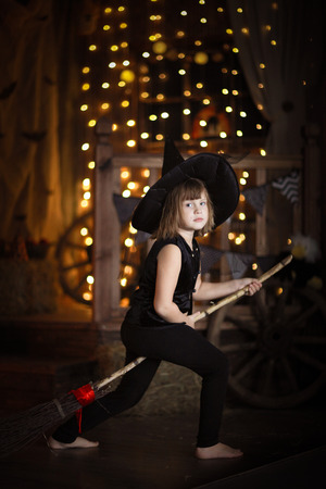 crazy funny Girl witch with broom . The concept of children games in Halloween, dark backgroundの写真素材
