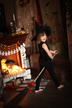 crazy funny Girl witch with broom . The concept of children games in Halloween, dark backgroundの写真素材