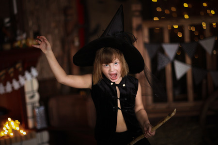 crazy funny Girl witch with broom . The concept of children games in Halloween, dark background