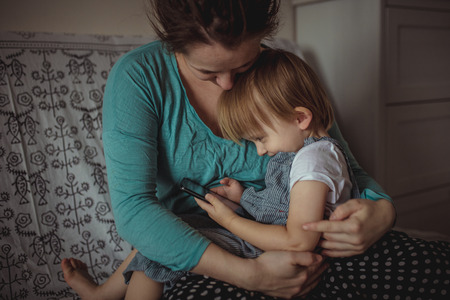 Pregnant mom and son Toddler playing with the phone, lifestyle. Real interior, toning, selective...
