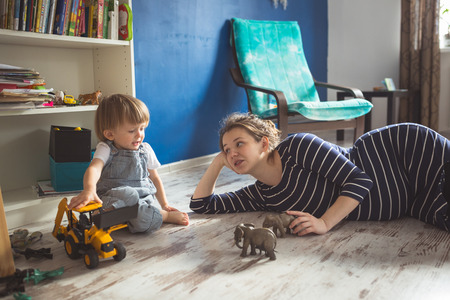 young pregnant mother with dreadlocks, and her son play  on floor, lifestyle, Real interior, toning,...