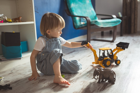 young pregnant mother with dreadlocks, and her son play and reading a book on sofa, lifestyle, real interior toningの写真素材