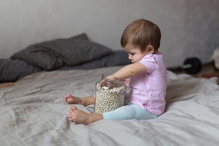baby playing on a bed of beans, concept early  development, natural toys, fine motor skills. Cosy...