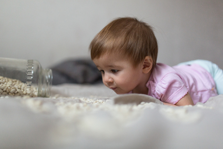 baby playing on a bed of beans, concept early  development, natural toys, fine motor skills. Cosy house, lifestyle, selective focus, toningの写真素材