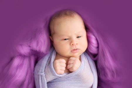 looking  newborn girl in the purple violet pink wool background, close-upの写真素材