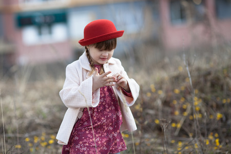 funny child girl with pigtails in hat and coat walks on spring park childhood lifestyleの写真素材