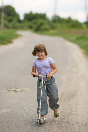 girl child riding a scooter on the road In the countryside, the concept of child safety, childhoodの写真素材