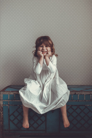 Funny girl in a nightgown retro on an old blue trunk, toningの写真素材