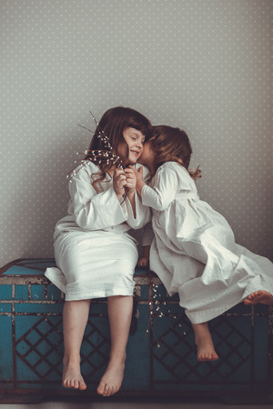 gentle sister girls in nightgowns retro, talking and hugging on chestの写真素材