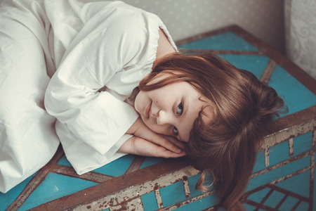 kid girl in nightgown retro on old trunkの写真素材