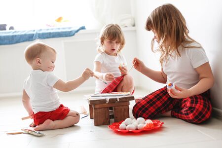 kids three siblings engaged in creativity, paint with watercolors eggs, Easter concept and children's creativityの写真素材