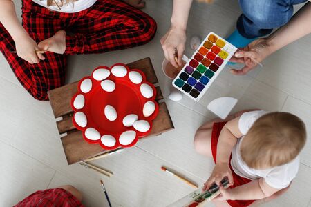 kids three siblings engaged in creativity, paint with watercolors eggs, Easter concept and children's creativityの写真素材