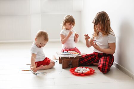 kids three siblings engaged in creativity, paint with watercolors eggs, Easter concept and children's creativityの写真素材