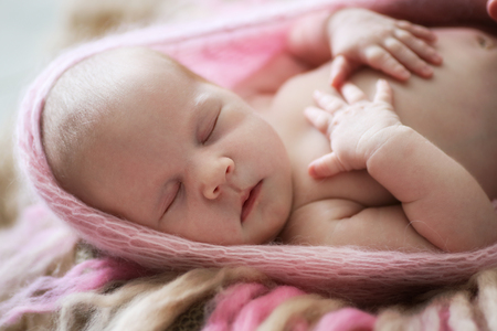 soft sleeper newborn baby girl in pink winding on  background of beige and pink woolの写真素材