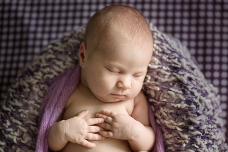 Charming baby sleeping in a basket, light purple background in polka dots, close-upの写真素材
