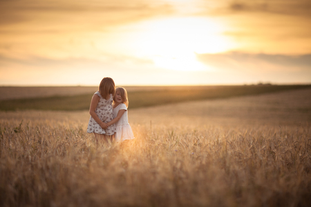 Sisters girls walk in the field with rye, happiness, freedom and family loveの写真素材