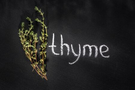 Fresh bunch of thyme on a chalky black board with a name, top view with a chalk, dark styleの写真素材