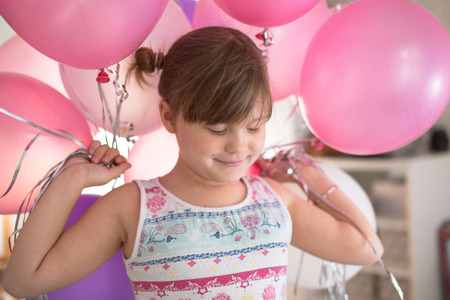 Naughty girl child rejoices with balloons, without a tooth, the concept of a happy childhood and a holidayの写真素材