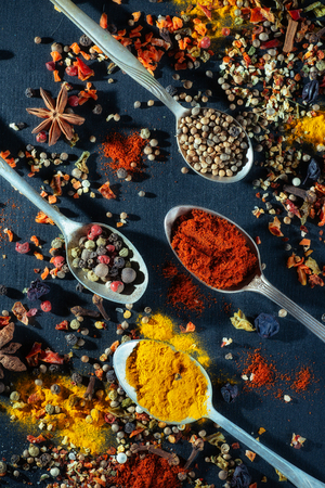 Spoons with different colored spices on a black background chalkboard,の写真素材