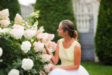 Beautiful woman girl in a tulle skirt with a bush of blooming hydrangea. Garden art and a beautiful...