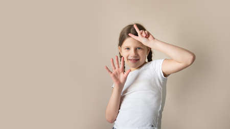 A child in a white T-shirt shows numbers on his fingers, beige background