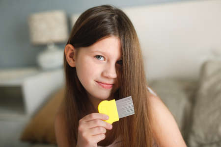Long-haired European girl child with lice comb, protection. Health and pharmaceutical concept, child health problems. doctor checks child's hair, head lice, possible lice infection.の写真素材