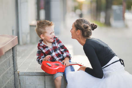 mother and son hugging playing ukulele outsideの写真素材