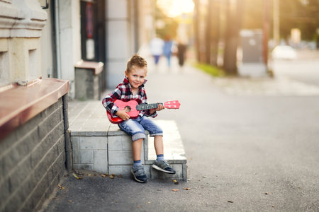 boy plays the ukulele on the street in summerの写真素材