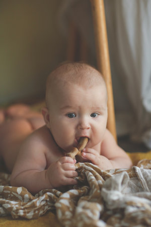 cute european baby 5 months old lies on a blanket on the floor. A child wearing amber teething beads...