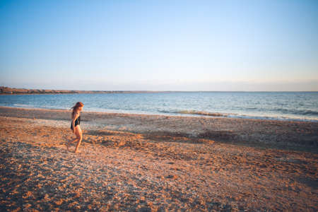 European girl child alone on the seashore, wide angle shooting, vacation with children at seaの写真素材