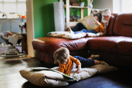 Funny children read books on soft mattresses on the couch and on the floor, real interior, dark styleの写真素材
