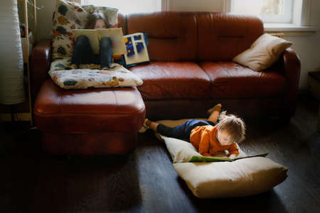 Funny children read books on soft mattresses on the couch and on the floor, real interior, dark styleの写真素材