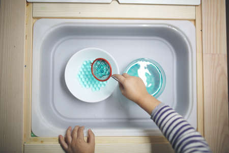 The child's hands are cleaning in the kitchen.