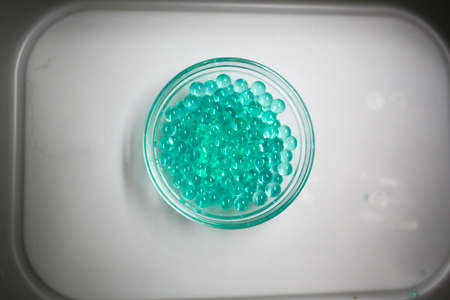 A closeup of a petri dish filled with green beads.