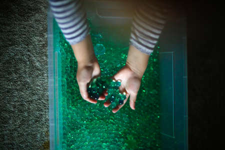 Hands of a child in a glass container with green water.の写真素材