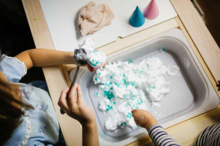 Little girl is decorating a cake with white and blue frosting.の写真素材