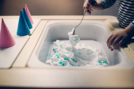 A little girl washes her hands in a basin with soap.の写真素材